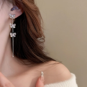 Détail de boucles d'oreilles pendantes en argent avec trois papillons en zircon