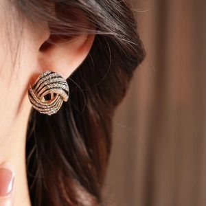 Gros plan de boucles d'oreilles nœud spirale vintage dorées avec strass sur mannequin