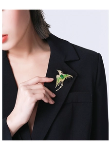 Detail of elegant phoenix brooch with green enamel and crystals on black blazer lapel