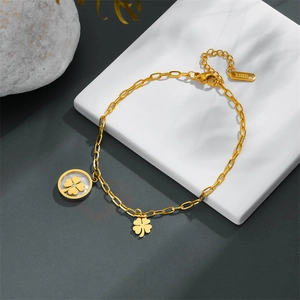 Elegant gold-tone stainless steel clover bracelet with white shell pendants on a stone base