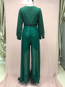 Detail of emerald green sequin jumpsuit featuring back zipper and black waist belt
