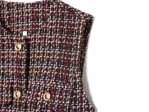 Detailansicht der rosa-schwarzen Tweed-Textur mit eleganten goldenen Metallknöpfen