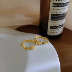 Ensemble de deux bagues cœur dorées avec design de chaîne sur plat en céramique