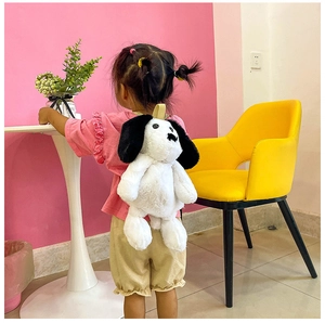 Toddler wearing a cute plush puppy backpack with long white fur and black ears