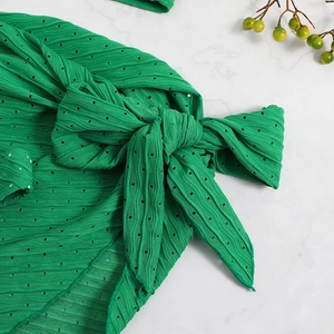 Macro shot of green pointelle knit fabric and side-tie bow detail of bikini skirt