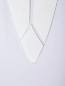 Detailed close-up of the white bodysuit featuring a deep V-neck and crisscross strap detail
