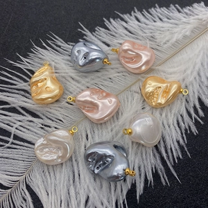 Irregular faux pearl pendants with gold loops on soft white feathers and black texture
