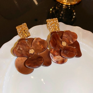 Detailed macro shot of vintage brown resin flower earrings with hammered gold metal studs