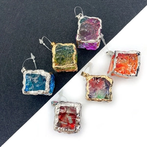 Close-up of teardrop-shaped gemstone pendants with metallic borders in six vibrant colors