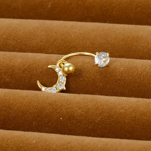 Macro detail of golden crescent moon belly ring with sparkling cubic zirconia on brown velvet