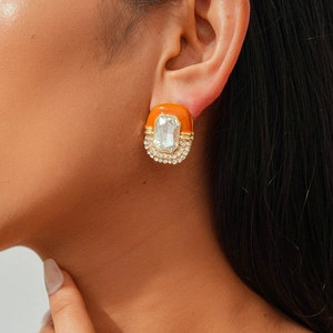 Close-up of vintage gold stud earring with orange enamel and crystal stones on a model