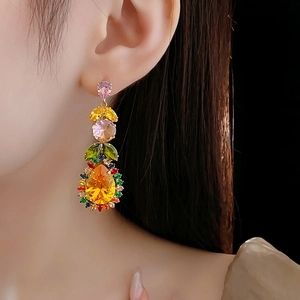 Detail of colorful leaf-shaped teardrop crystal earrings worn on model against black background