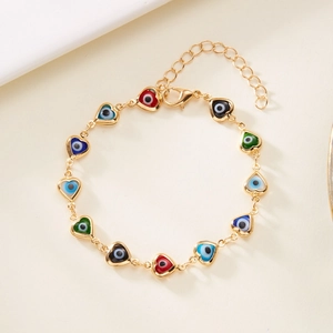 Macro detail of gold chain bracelet with colorful enamel heart evil eye charms