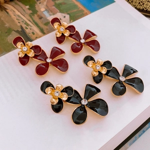 Detail of red and black flower earrings with gold edges and crystal centers