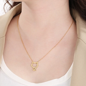 Détail d'un collier doré avec pendentif chat évidé porté par un mannequin femme