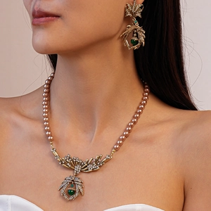 Detail of vintage necklace with pearls, rhinestones, and green pendant on model