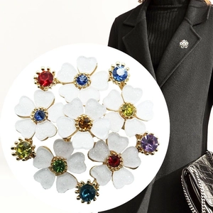 Elegante spilla floreale bianca con strass colorati sul bavero di un cappotto nero