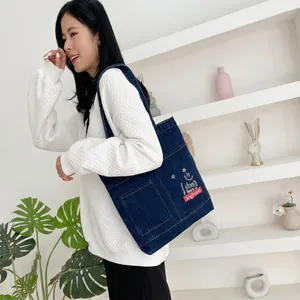 Detail of dark blue denim tote bag with white smile embroidery and star patterns