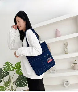 Dettaglio della borsa tote in denim blu scuro con ricamo bianco a sorriso e stelle