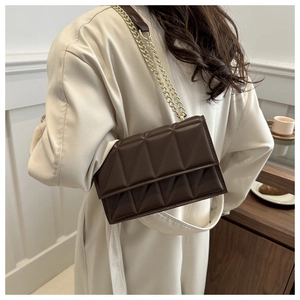 Close-up of a dark brown crossbody bag featuring geometric quilting and a gold chain strap