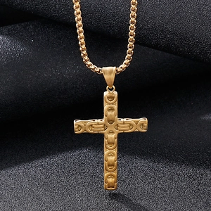 Détail macro d'un pendentif croix dorée avec maillons texturés sur fond de soie