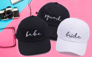 Top view of embroidered Squad Bride baseball caps on a colorful split background