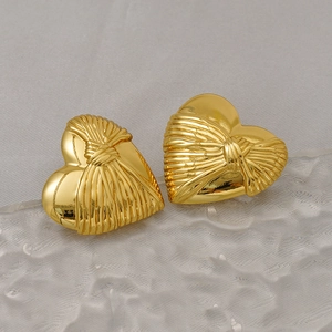 Detail of gold heart earrings featuring vintage pleated texture and ribbon knot design