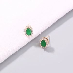 Macro detail of emerald style green oval gemstone earrings with sparkling white crystals
