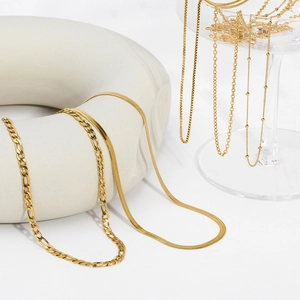 Detail of diverse golden hip-hop necklaces displayed on white ceramic and glass