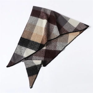 Detail of multi-color plaid knit scarf with brown and grey patterns on white backdrop