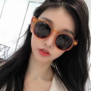 Vintage round tea-colored sunglasses with translucent frames and grey lenses on a model