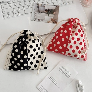Detailed view of red and black polka dot drawstring fabric pouches on a white desk setup