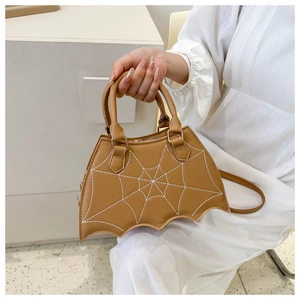 Detail of a brown bat-shaped leather handbag featuring white spider web embroidery