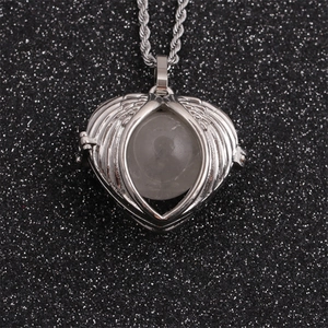 Silver angel wing heart locket necklace with transparent sphere on dark background