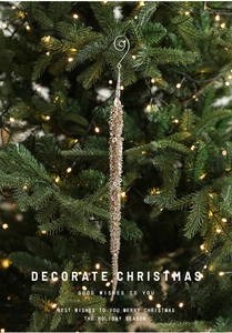 Close-up of champagne gold sequined icicle ornament hanging on a Christmas tree branch