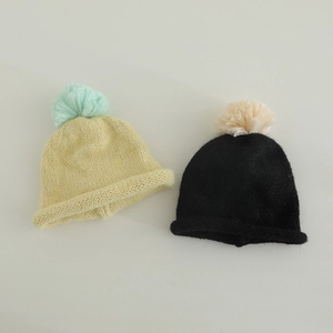 Close-up of knit texture and fluffy pom-pom detail on colorful winter beanies for kids