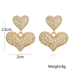 Dettaglio degli orecchini a doppio cuore dorati da 2,5 cm con zirconi bianchi