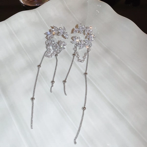 Detail of silver crescent ear cuff with zircon flower and long pearl tassel drop