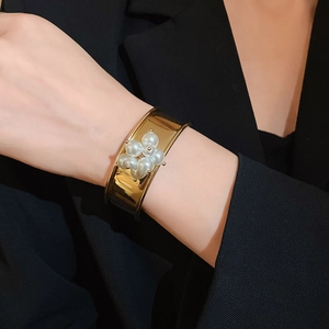 Polished gold cuff bracelet featuring a cluster of white pearls with an open design