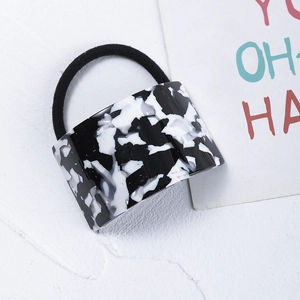 Macro detail of acetate geometric charm with black and white marble pattern on hair tie