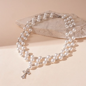 Détail d'un collier de perles double épaisseur avec un pendentif croix en zircon