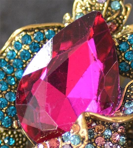 Macro detail of a vintage brooch with large pink pear gemstone and colorful crystals