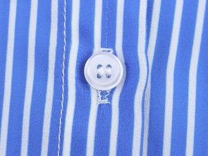 Detailed close-up of blue and white striped shirt fabric with white button and neat stitching
