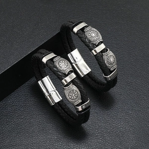 Close-up of black braided leather bracelets with silver magnetic clasp and compass beads