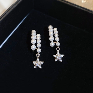 Macro view of gold-plated flower earrings with freshwater pearls and star pendants