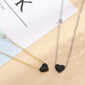 Détail de colliers dorés et argentés avec pendentifs cœur noirs et cristaux brillants