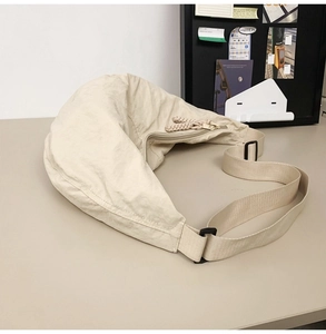 Détail du sac bandoulière beige en nylon avec tissu plissé et tirette de zip tressée