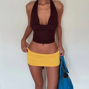 Détail du haut dos nu marron foncé et de la mini-jupe moulante jaune éclatant