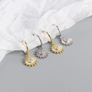 Detailed macro view of gold and silver sunburst earrings set with clear gemstones