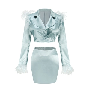 Détail de l'ensemble en satin bleu clair avec plumes blanches sur les poignets et épaules